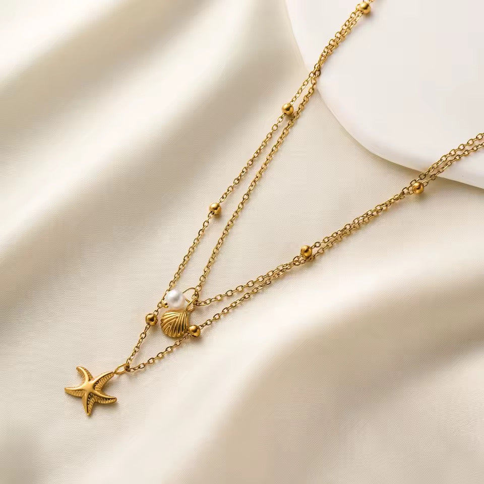 Collana elegante a doppio filo in acciaio dorato waterproof con stella marina, conchiglia e perla da donna.