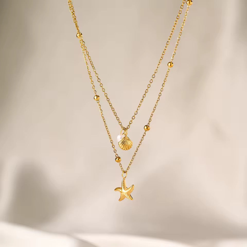 Collana elegante a doppio filo in acciaio dorato waterproof con stella marina, conchiglia e perla da donna.
